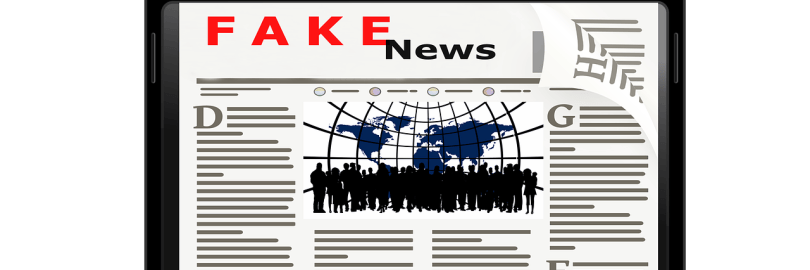 Auf dem Bildschirm eines aufgeklappten Laptops ist das Wort Fake News zu lesen