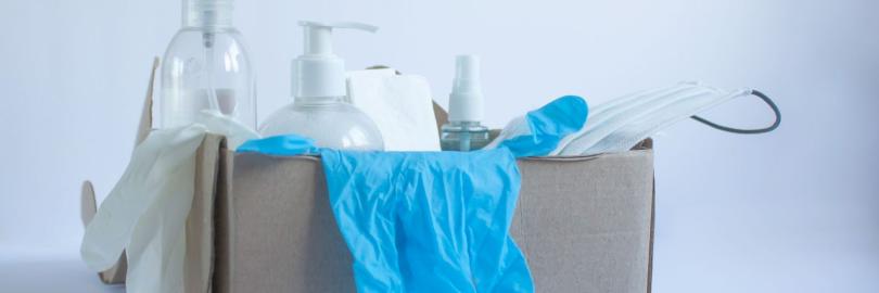 Karton mit Pflegemitteln wie Einmalhandschuhen, OP-Maske, Spray