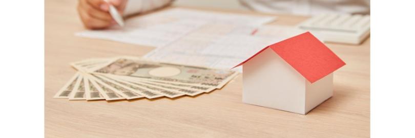 Papierhaus, Geld,  Unterlagen, eine männliche Hand mit Kugelschreiber