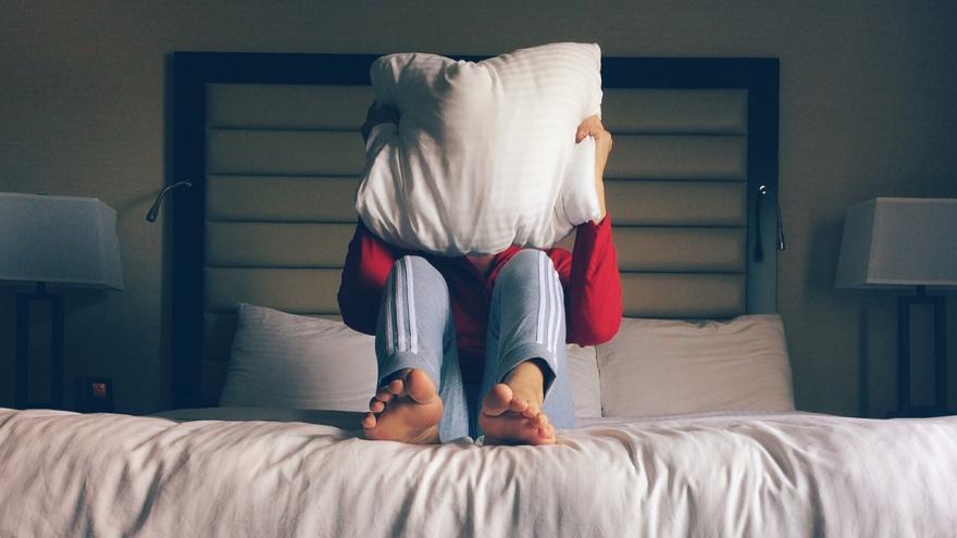 Mann auf einem Bett im Hotelzimmer mit Kissen vor den Augen