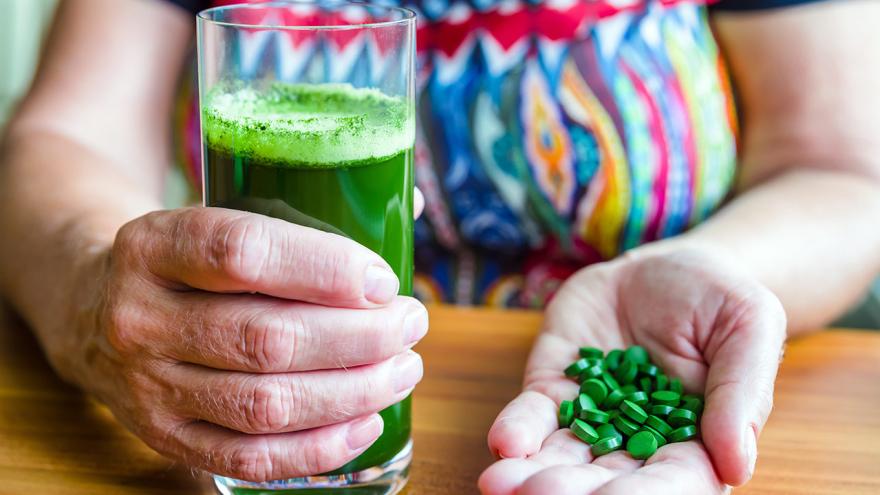 Chlorella im Glas zum Trinken und auf der Hand als Pillen