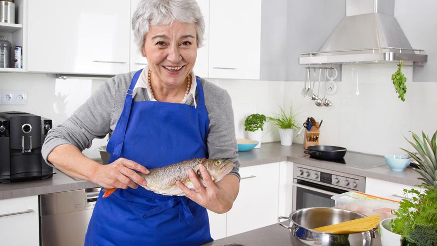Eine Dame bereitet in der Küche Fischgericht vor