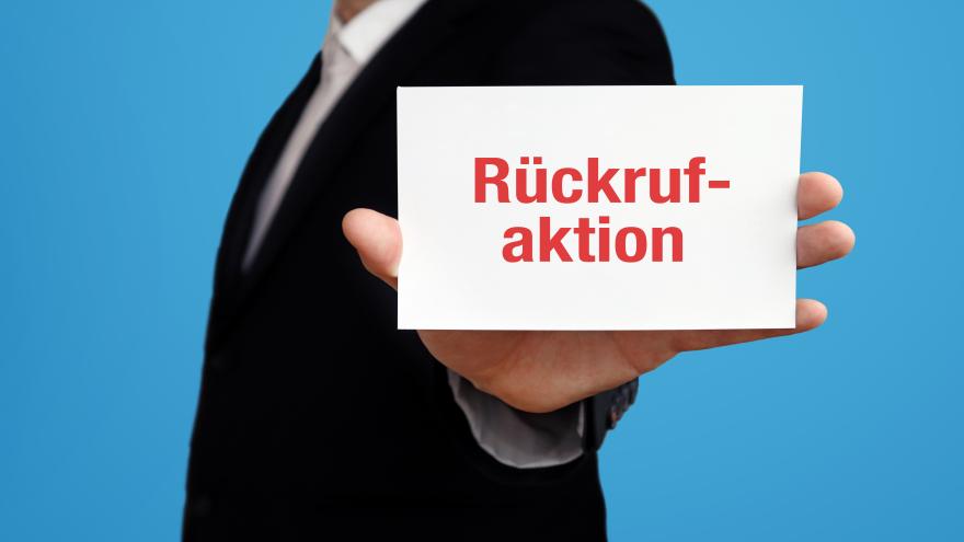 Ein Mann im Anzug hält einen Zettel in der Hand mit der Aufschrift "Rückrufaktion".