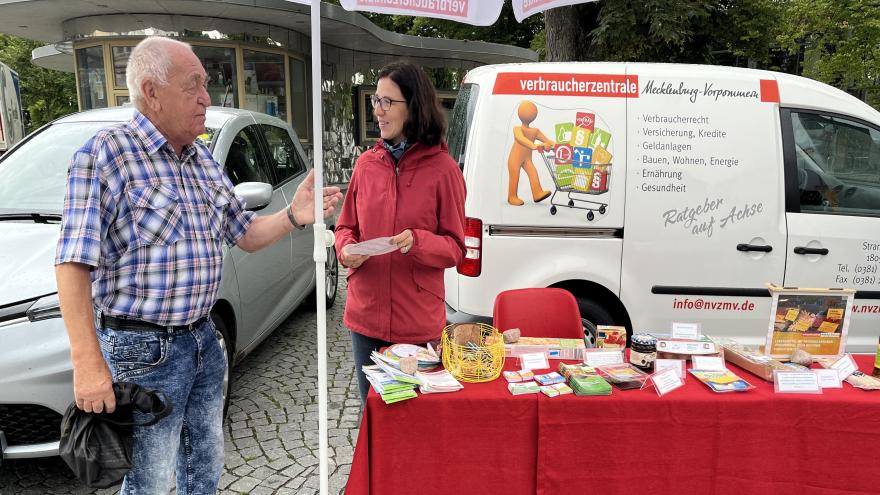zwei unterhaltende Menschen vor dem Verbraucherzentralen Auto