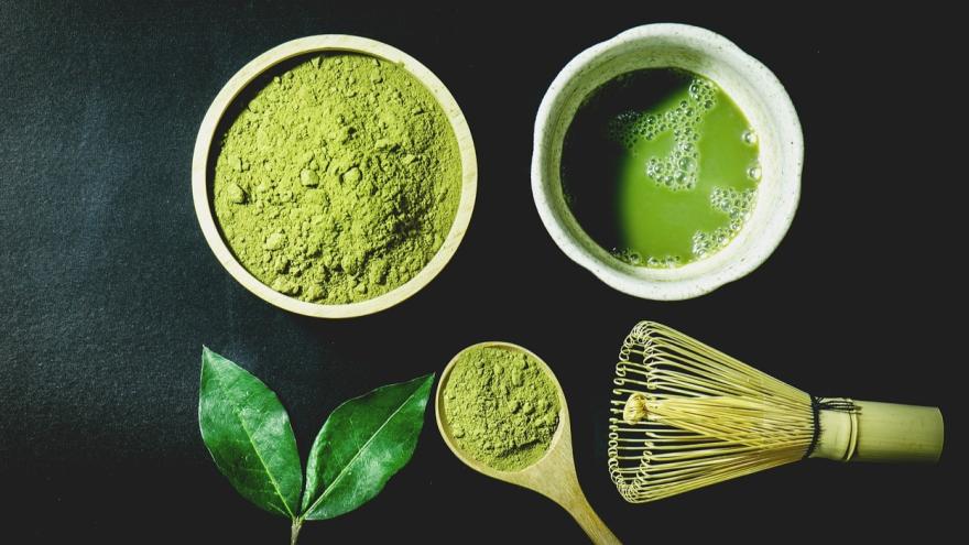 Matcha-pulver mit schneebesen und portionsloeffel, grünes Matchablatt