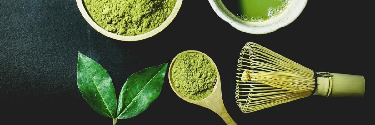 Matcha-pulver mit schneebesen und portionsloeffel, grünes Matchablatt