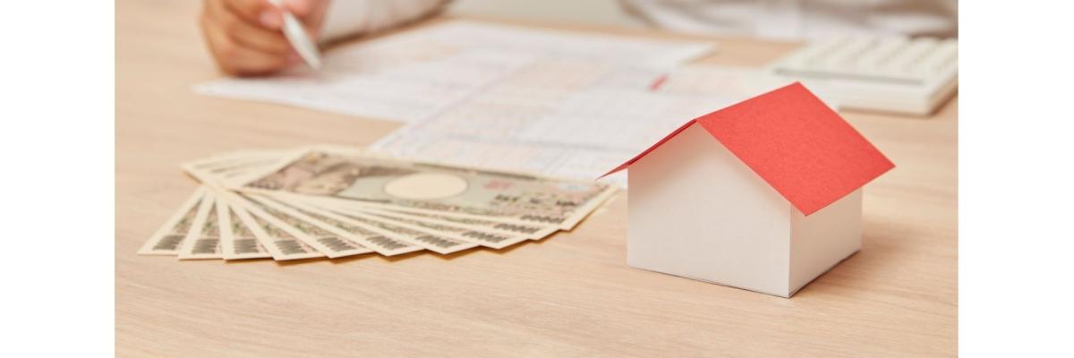 Papierhaus, Geld,  Unterlagen, eine männliche Hand mit Kugelschreiber