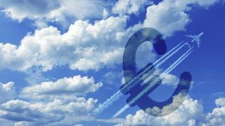 blauer Himmel mit einem Flugzeiúg, das durch ein Euro-zeichen fliegt