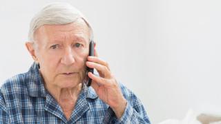 alter Mann im Schlafanzug, telefoniert