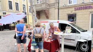 das Auto der Verbraucherzentrale mit einem Infostand davor, vor dem stand stehen Menschen