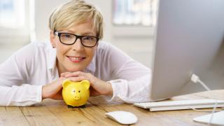 Eine Frau stützt sich mit Kopf und Händen auf ein Sparschwein