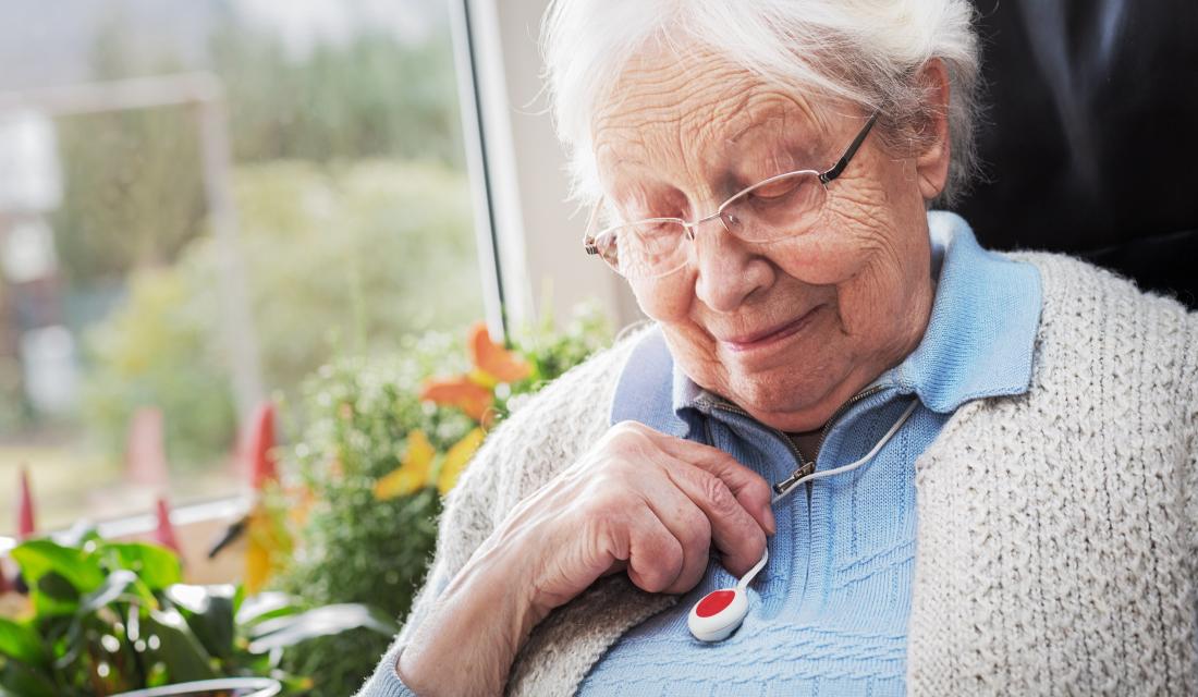 Seniorin trägt Hausnotruf-Knopf als Kette um den Hals
